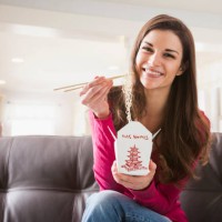 caucasian woman eating chinese food on sofa - junk food stock pictures, royalty-free photos & images