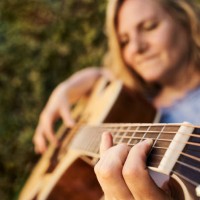 caucasian woman playing acoustic guitar in the garden. musical concept. - concert stock pictures, royalty-free photos & images