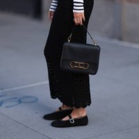 Charlotte Groeneveld is seen wearing a black/white striped long-sleeved top; a black, perforated, high-waisted cut maxi skirt; a black leather bag...