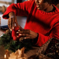 charming young black woman decorating a christmas wreath - home decoration stock pictures, royalty-free photos & images