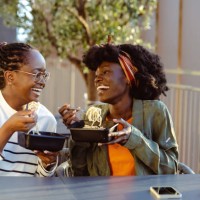 cheerful african american female friends eating fast food meal in the city - junk food stock pictures, royalty-free photos & images