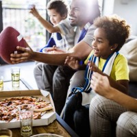 cheerful black family cheering while watching rugby match on tv at home. - junk food stock pictures, royalty-free photos & images