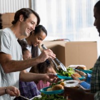 cheerful caucasian man serves healthy meal in soup kitchen - food stock pictures, royalty-free photos & images