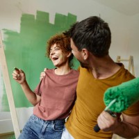 cheerful couple embracing while painting their new home. - home decoration stock pictures, royalty-free photos & images