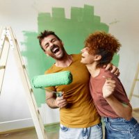 cheerful couple having fun while painting their new apartment in green. - home decoration stock pictures, royalty-free photos & images