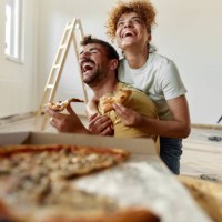 cheerful couple in love eating pizza on a break from home renovation process. - junk food stock pictures, royalty-free photos & images