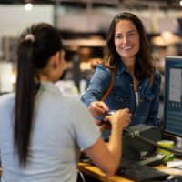 cheerful female customer making a contactless payment with credit card at a furniture store smiling - home decoration stock pictures, royalty-free photos & images