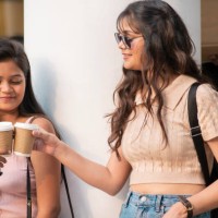 cheerful female friends enjoying coffee takeaway while walking on city street - junk food stock pictures, royalty-free photos & images