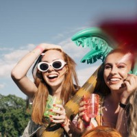 cheerful female friends enjoying drinks at music concert against sky in summer - concert stock pictures, royalty-free photos & images