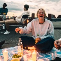 cheerful female with friends enjoying on building terrace during sunset - food stock pictures, royalty-free photos & images