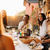 cheerful friends talking while enjoying dinner at dining table in party - food stock pictures, royalty-free photos & images
