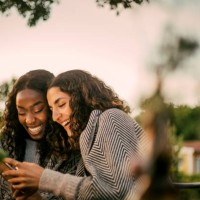 cheerful friends using phone in backyard during social gathering - garden decoration photos et images de collection
