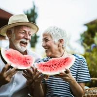 cheerful mature couple having fun while eating watermelon during picnic day in nature. - food stock pictures, royalty-free photos & images