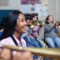 cheerful mixed ethnicity asian girl with saxophone in band orchestra class - concert stock pictures, royalty-free photos & images