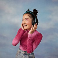cheerful teenage girl listening to music through wireless headphones against colored background - fashion stock pictures, royalty-free photos & images