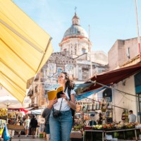 cheerful tourist reading a travel guide in ballarò market, palermo, sicily, italy - travel photos et images de collection
