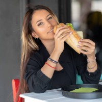 cheerful woman eating a sandwich - junk food stock pictures, royalty-free photos & images