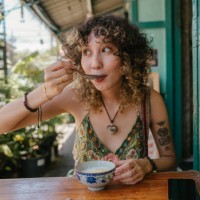 cheerful woman who sitting in front of restaurant enjoying eating tasty thai dessert. - food stock pictures, royalty-free photos & images