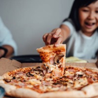cheerful young girl holding a slice of pizza - junk food stock pictures, royalty-free photos & images