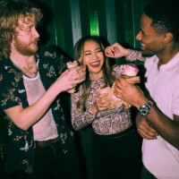 cheerful young multiracial friends eating wrap sandwiches together at nightclub - concert stock pictures, royalty-free photos & images