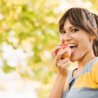 cheerful young woman eating an apple - food stock pictures, royalty-free photos & images