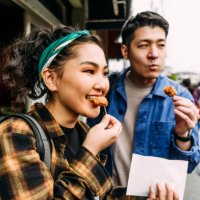 cheerful young woman eating street food with friends - food stock pictures, royalty-free photos & images
