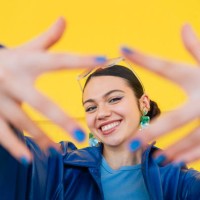 cheerful young woman smiling, framing face with hands against bright yellow backdrop - fashion stock pictures, royalty-free photos & images