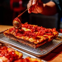 Chef Michael Chambers, in typical Detroit fashion, sauces the top of a Detroit original pepperoni pizza at Red Light photographed for Weekend in...
