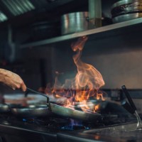 chef preparing a flambe dish at gas stove in restaurant kitchen - food stockfoto's en -beelden