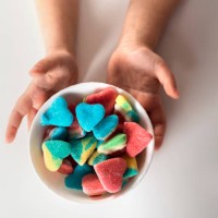 child hands holds a bowl with colorful sour and sweet candies on a white background. - junk food stock pictures, royalty-free photos & images