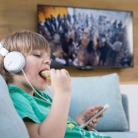 Child playing with a smartphone next to the television.