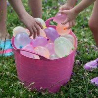 children grabbing water balloons from a bucket - garden decoration stock pictures, royalty-free photos & images