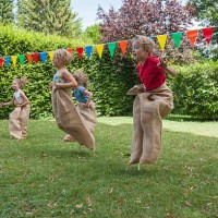 children having a sack race in garden on a birthday party - garden decoration stock pictures, royalty-free photos & images