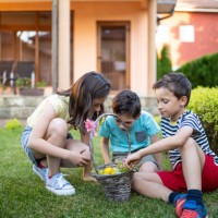 children sharing a basket of easter eggs in a garden - garden decoration stock pictures, royalty-free photos & images