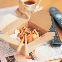 chinese meal in a carton by a remote control and a magazine - junk food stock pictures, royalty-free photos & images