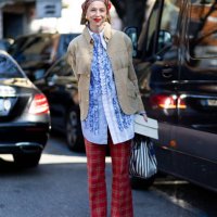 Chloe King wears a red printed bandana, gold pendant earrings, a blue shirt with ruffles, a beige suede jacket with fringes, red checked flared...