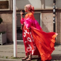 Chloe King wears white long dress with red flowers, orange and pink long coat and a head scarf outside the Gestuz show during day four of the...