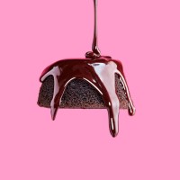 chocolate frosting being poured onto chocolate cake with pink background - food stock pictures, royalty-free photos & images