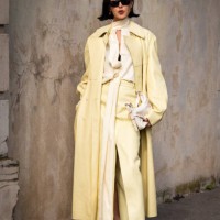 Chriselle Lim wears a light yellow blouse, yellow trousers, yellow leather long coat, beige heels and white Givenchy bag, outside Givenchy, during...