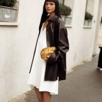 Clara Kong Vila wears white dress, brown high heels, black leather jacket and yellow bag outside the LOEWE presentation during the Womenswear...