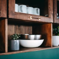 classic kitchen interior with brown coloured wooden cabinets and shelves against dark green coloured wall. crockery, dishes and houseplants on the shelves - home decoration stockfoto's en -beelden