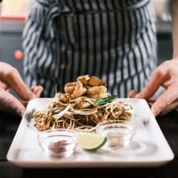 classic thai pad thai noodles with stir-fried shrimp, fresh vegetables, lime, and condiments elegantly presented on a white plate in a traditional restaurant setting - junk food stock pictures, royalty-free photos & images