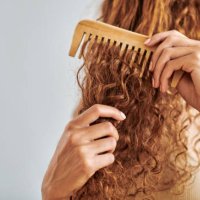 cleaning, beauty and hair care by woman brush and style her natural, curly hair in bathroom in her home. hygiene, frizz and damage control with female hands comb natural hair in morning routine - hairstyle stockfoto's en -bee