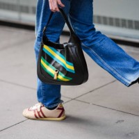 Close-up detail view of a black leather Gucci bag with yellow and blue printed stripes, during New York Fashion Week, on February 12, 2024 in New...