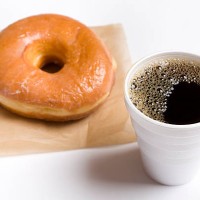 close-up of a cup of black coffee and a glazed donut - junk food stock pictures, royalty-free photos & images