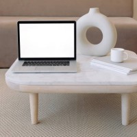 close-up of an open laptop computer on a coffee table next to a ceramic vase and a cup on a stack of books - home decoration stock pictures, royalty-free photos & images
