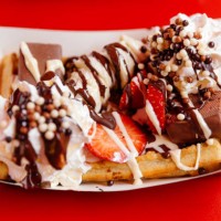 close-up of belgian waffle with strawberry, banana, cream and chocolate toppings - junk food stock pictures, royalty-free photos & images