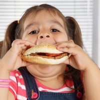 close-up of caucasian girl with pigtails eating a burger - junk food stock pictures, royalty-free photos & images