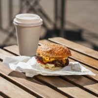 close-up of cheeseburger and take-out coffe on wooden table - junk food stock pictures, royalty-free photos & images