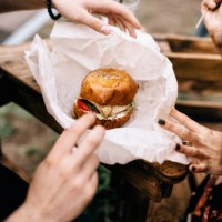 close-up of couple with a hamburger outdoors - junk food stock pictures, royalty-free photos & images
